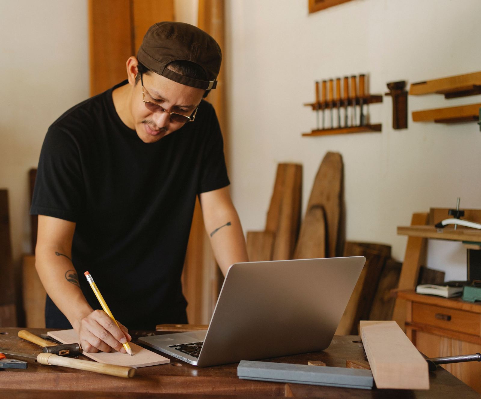 A carpenter writing up an invoice at his laptop in his workshop