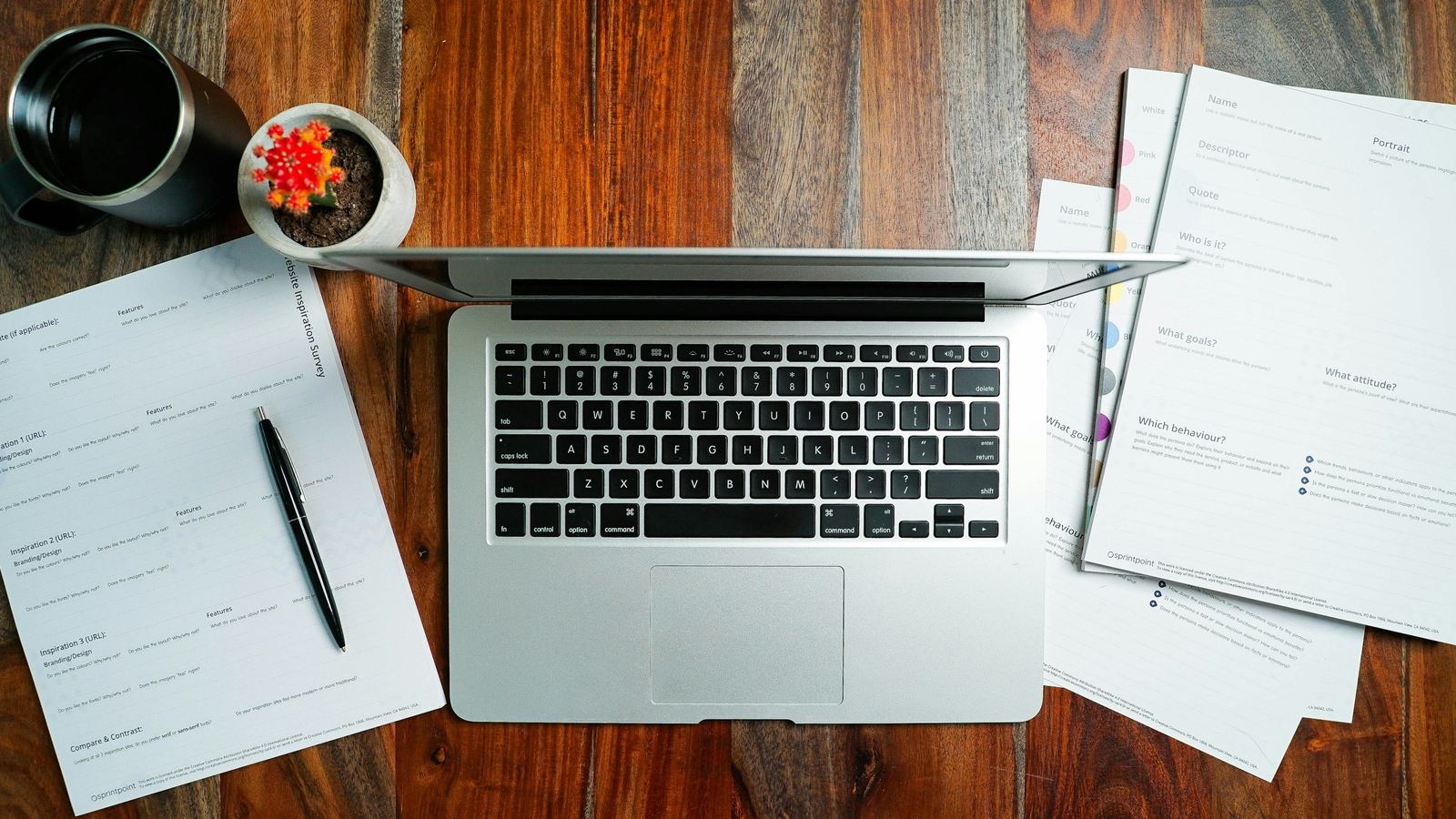 A laptop and printed invoices on a wooden desk